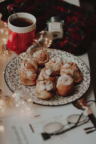 meal bread with cream toppings on round plate near lighted bulb and white and red ceramic mug dish