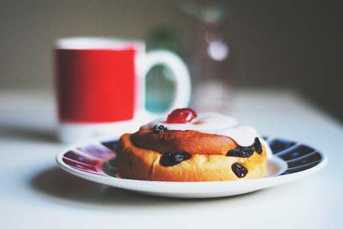dessert bread with raisins on saucer beside white and red mug cup