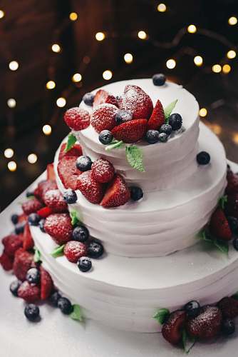 fruit close-up photography of 3-tier vanilla cake with blueberry and strawberry toppings blueberry