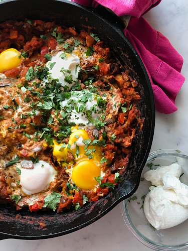 bowl cooked meat with eggs in skillet shakshuka