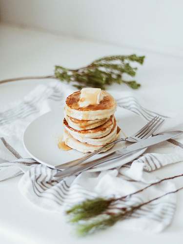 pancake cooked pancake on round white ceramic plate beside butter knife and fork plate