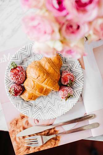 dessert croissant bread and stawberries on beside fork and knife pastry