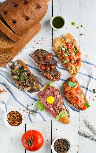 tomato flay lay photography of sliced breads with beef and vegetables on top and dips flora