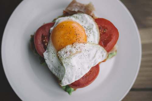 cream fried egg with black pepper and sliced tomatoes egg