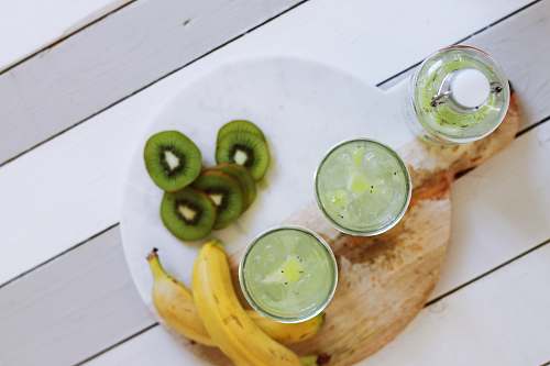 drink fruit juice cups beside yellow bananas on plate beverage