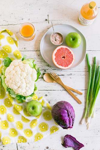 plant green apple, sliced of grapefruit with purple cabbage, scallions and cauliflower on table produce