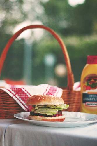 burger hamburger on ceramic plate beside picnic basket meal