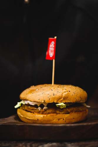 bread hamburger on wooden surface with small flag burger