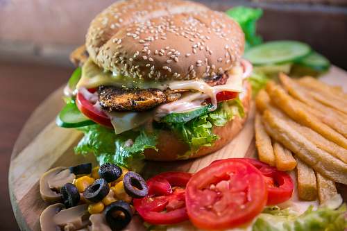 burger hamburger with vegetables and meat beside French fries donut