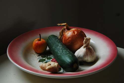 garlic onion, garlic, ginger, and green vegetable on round white and red plate vegetable