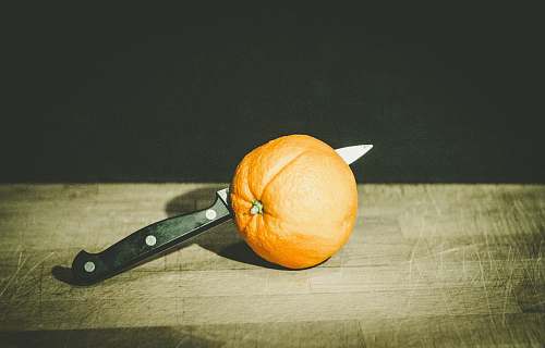 fruit orange fruit and gray and black knife on brown wooden board low-light photography orange