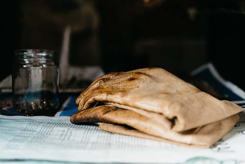 bread pair of brown leather gloves beside glass jar on newspaper pita