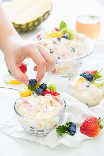 fruit person holding blueberry fruit with hands on top of fruit salad blueberry