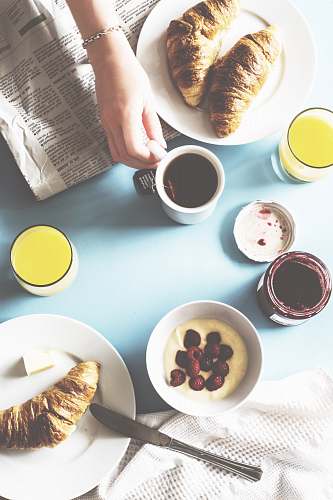 breakfast person holding white ceramic mug on table croissant
