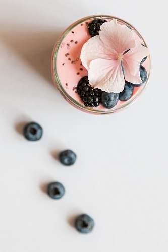 drink pink beverage on glass with blackberries and pink flower on top pink