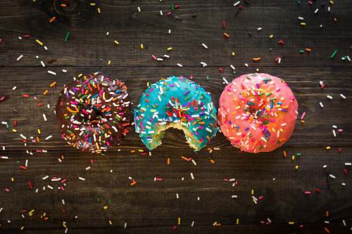 paper pink, blue, and chocolate with sprinkles doughnuts on table confetti