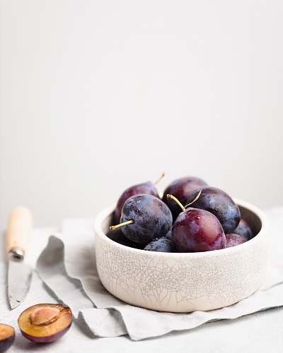 produce purple grapes on round white bowl plum