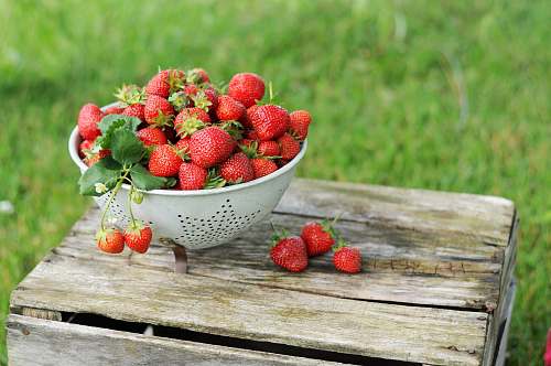 plant red strawberries on wooden surface and in colandar fruit