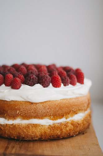 confectionery round cake with white frosting topped with red raspberries sweets