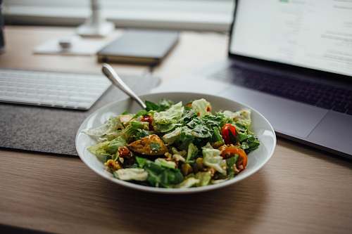 salad salad on white ceramic bowl on top of table near laptop meal