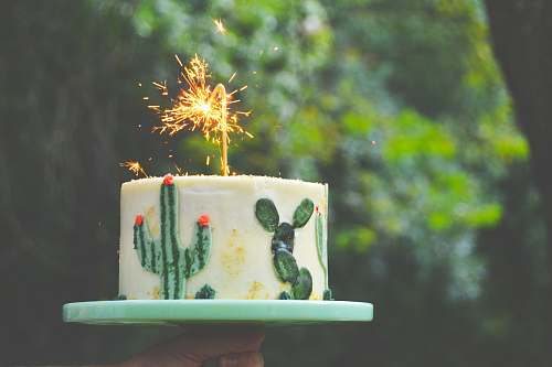cake selective focus photograph of white and green cake with sparkler candle dessert