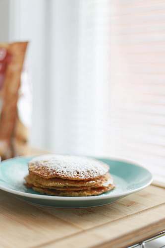 pancake selective focus photography of four piece pancakes with powdered sugar on top in blue ceramic plate bread