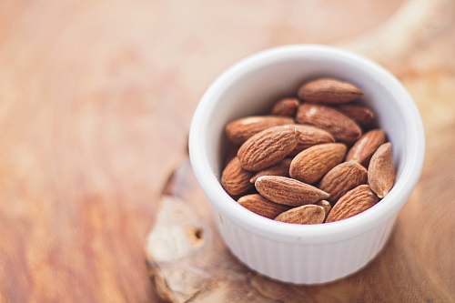 healthy shallow focus photography of almonds in white ceramic bowl almond
