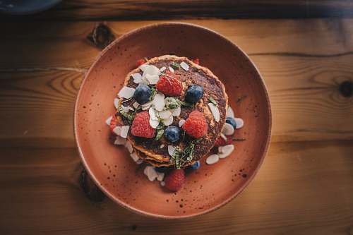 bowl shallow focus photography of pancake with strawberries and blueberries on top cake