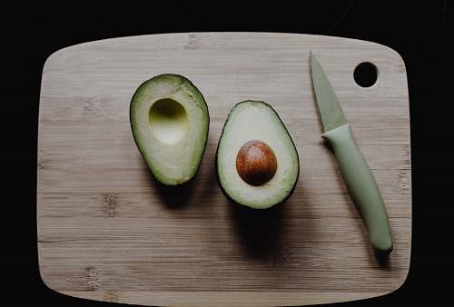 fruit sliced avocados on top of brown wooden chopping board in top view photography avocado