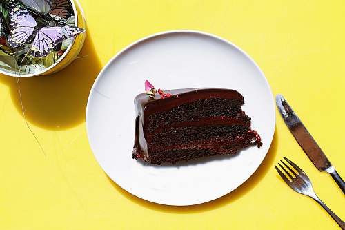 cutlery sliced chocolate moist cake in plate near gray stainless steel fork and knife fork