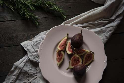 fruit sliced fruit on plate beside green leaves fig