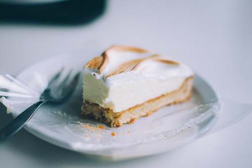 dessert sliced of cake on round white plate with silver fork cheesecake