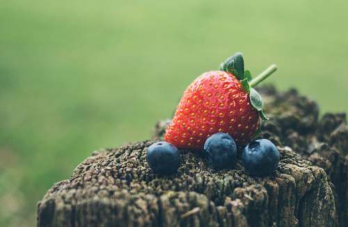 fruit strawberry and three blueberries in closeup photography strawberry