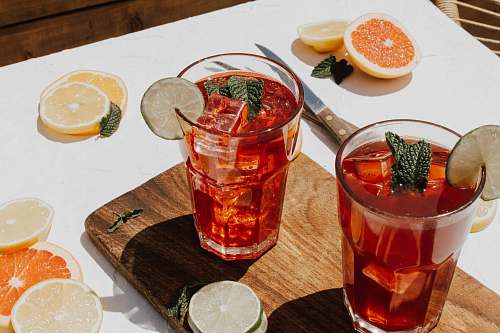 plant two clear drinking glasses with filled red liquid citrus fruit