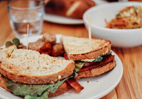 meal two sliced of sandwich on plate near bowl and drinking glass glass