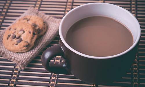 cup white and brown ceramic cup with coffee near cookies hot chocolate