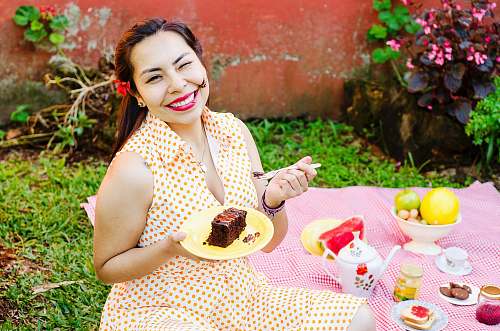 person woman in polka-dot dress holding fork and plate with slice of cake meal