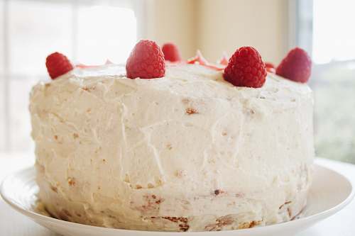 plant round white icing covered cake with raspberries raspberry