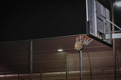 clothing basketball hoop near gray chain link fence during night sport