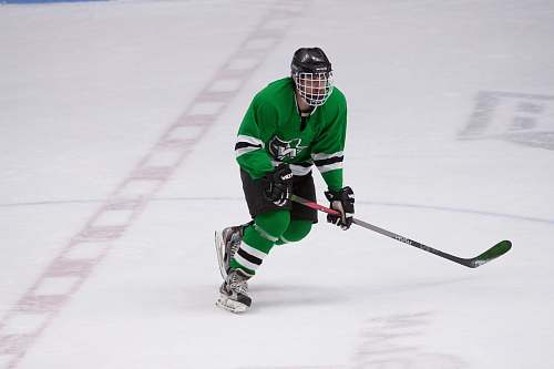 human hockey player wearing full gear on ice skating field person