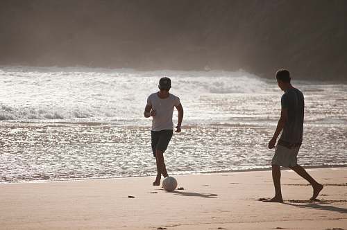 clothing men playing football in beach shorts