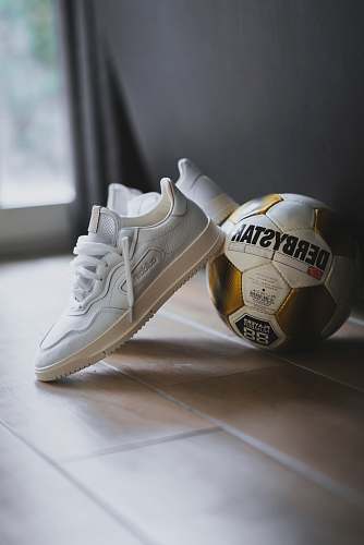 clothing pair of white Adidas low-top sneakers beside Derbystar soccer ball footwear
