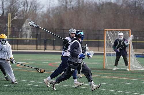 clothing people playing lacrosse on grass field helmet