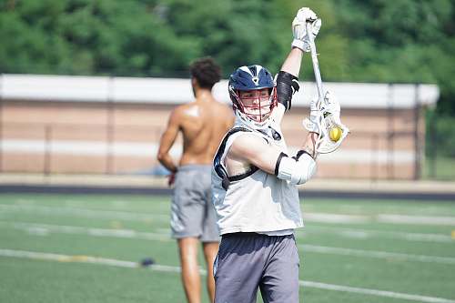 clothing person holding lacrosse stick across topless man wearing gray shorts human