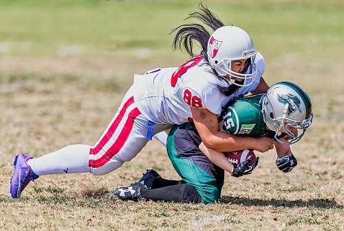 helmet player grabbing another player on ground during daytime clothing