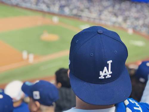 human selective focus photography of person wearing LA Dodgers cap looking at field person