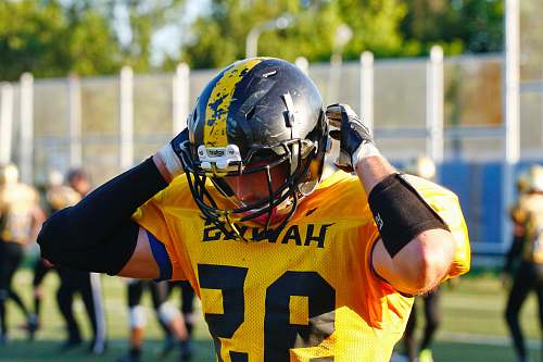 clothing shallow focus photo of man wearing yellow Hawks 95 football jersey helmet