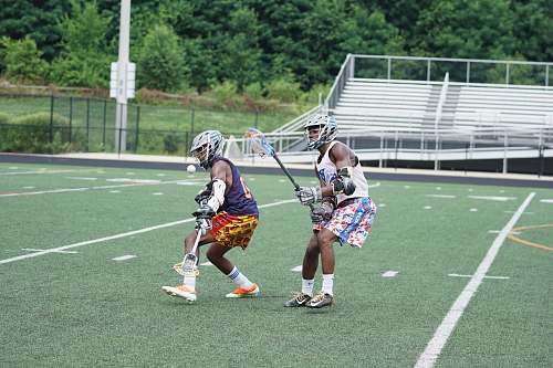 human two men holding lacrosse sticks on green field person
