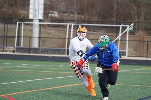 clothing two men playing lacrosse game on field helmet