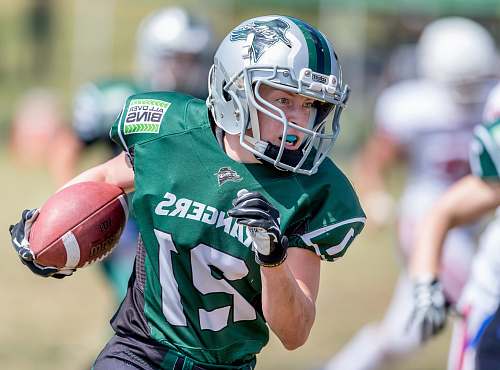 clothing woman holding football while running near players helmet